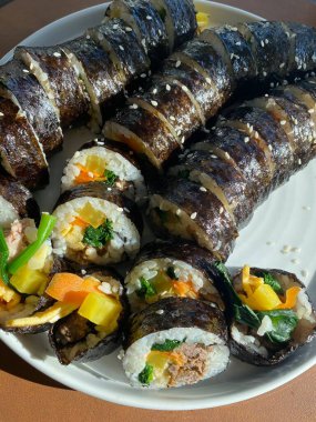 Taze sebzelerle, baharatlı pirinçlerle ve gevrek yosunlara sarılmış lezzetli proteinlerle dolu nefis kimbap dürümleri. Her ısırıkta lezzet ve dokuların mükemmel bir kombinasyonu.