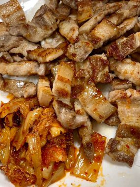 Izgara samgyeopsal, kalın domuz eti dilimleri çıtır çıtır ve taze et. Klasik bir Kore barbekü deneyimi için marul, sarımsak ve sosla servis ediliyor..