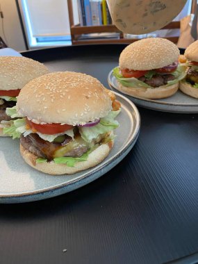 Ağzını sulandıran bir burger, sulu bir köfte, taze marul, domates ve erimiş peynir, hepsi yumuşak bir çöreğin içinde. Yemek fotoğrafçılığı için mükemmel, klasik konforlu yiyeceklere düşkünlük sergiliyor..