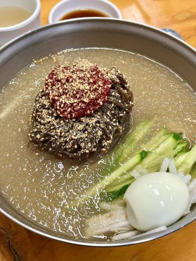 Chilled, chewy naengmyeon noodles in tangy broth paired with juicy, savory mandu dumplings, offering a perfect balance of refreshing coolness and hearty comfort in every delicious Korean bite.