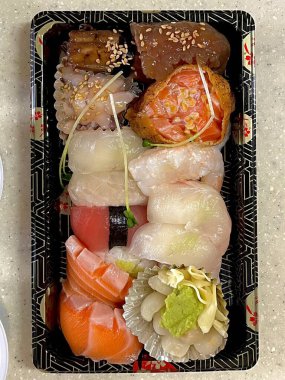 Çeşitli malzemeler ve canlı renklerle sanatsal olarak düzenlenmiş taze suşi çeşitleri. Bu geleneksel Japon yemeği bir deneyim için sirkeli pirinç, deniz ürünleri ve sebzeleri birleştirir..