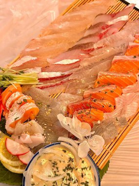 Taze ve narin sashimi dilimleri, canlı renkler ve mükemmel kesimlerle güzelce sunuluyor. Bu geleneksel Japon lezzeti kaliteli deniz ürünlerinin saf tatlarını vurgular..