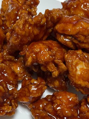 Kızarmış Kore tavuğu, tatlı ve baharatlı sosla mükemmel bir şekilde jölelenmiş. Yemek fotoğrafçılığı ve menüler için idealdir. Bu sevilen yemeğin dayanılmaz çıtırtısını ve lezzetini sergiler..