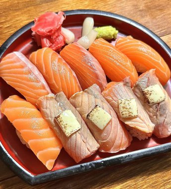 Mükemmel şekilli pirincin üzerine parlak turuncu dilimli taze somon balığı. Basit, renkli ve iştah açıcı bir sunum için yeşil yapraklar ve turpla süslenmiş.