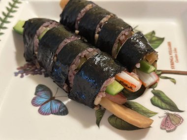 Taze sebzelerle, baharatlı pirinçlerle ve gevrek yosunlara sarılmış lezzetli proteinlerle dolu nefis kimbap dürümleri. Her ısırıkta lezzet ve dokuların mükemmel bir kombinasyonu.