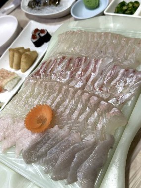 Taze ve narin sashimi dilimleri, canlı renkler ve mükemmel kesimlerle güzelce sunuluyor. Bu geleneksel Japon lezzeti kaliteli deniz ürünlerinin saf tatlarını vurgular..