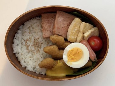 Geleneksel bir Kore dozirak 'ı. Pirinç, çeşitli banchan ve tuzlu proteinlerle güzelce düzenlenmiş. Dengeli ve görsel olarak davetkâr, canlı lezzetlerle dolu taşınabilir bir yemek..