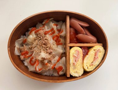 Geleneksel bir Kore dozirak 'ı. Pirinç, çeşitli banchan ve tuzlu proteinlerle güzelce düzenlenmiş. Dengeli ve görsel olarak davetkâr, canlı lezzetlerle dolu taşınabilir bir yemek..