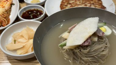 Soğuk ve ferahlatıcı Kore naengmyeon eriştesi, dilimlenmiş salatalık, turp ve haşlanmış yumurta ile servis edilir. Sıcak yaz günleri için nefis, keskin bir yemek..