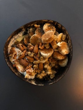 Taze renkli meyvelerle kaplı bir kasede servis edilen Yunan yoğurdu, kremalı pürüzsüz bir doku, canlı doğal renkler ve detaylı bir şekilde ferahlatıcı bir görünüş sunuyor.