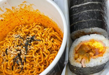 Kimbap ve Ramyun, mükemmel bir Kore karışımı! Lezzetli pirinç rulolarının yanında sebze, et ve turşu ile baharatlı ve rahatlatıcı ramen ye. Günün her saatinde doyurucu bir yemek..
