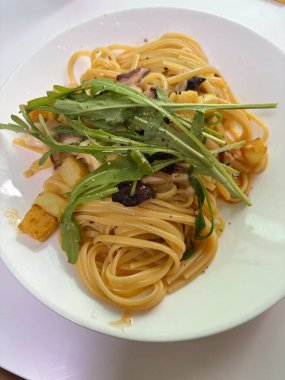 Bir tabak spagetti makarnası, mükemmel pişirilmiş ve üzerine bol marinara sosu ve taze otlar konmuş. Yemek fotoğrafçılığı ve menüler için ideal, İtalyan mutfağının kalbini lezzetli bir şekilde yakalamak..