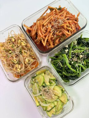 İçinde kimchi, baharatlı sebze, turp turşusu ve marine edilmiş yosun bulunan renkli bir banchan çeşidi. Bu Kore mezeleri masaya çeşitli dokular ve tatlar getiriyor..