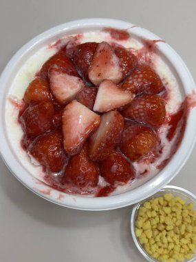 Yumuşak ve yumuşak çilekli bingsu, ince buzlu buzlu tatlı çilek şurubu ve taze çilek dilimleri. Ferahlatıcı ve lezzetli bir Kore tatlısı, serin ve meyveli bir ikram için mükemmel..