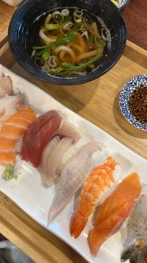 Çeşitli malzemeler ve canlı renklerle sanatsal olarak düzenlenmiş taze suşi çeşitleri. Bu geleneksel Japon yemeği bir deneyim için sirkeli pirinç, deniz ürünleri ve sebzeleri birleştirir..