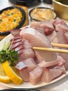 Taze ve narin sashimi dilimleri, canlı renkler ve mükemmel kesimlerle güzelce sunuluyor. Bu geleneksel Japon lezzeti kaliteli deniz ürünlerinin saf tatlarını vurgular..