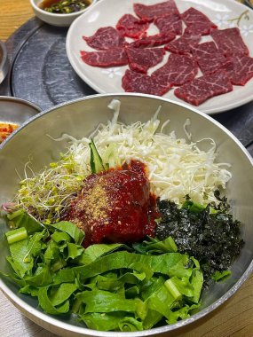 Bibimbap, çeşitli sebzeler, gochujang ve sıklıkla dilimlenmiş etin eşlik ettiği kızarmış yumurta ile süslenmiş canlı bir Kore pirinç yemeği. Karıştırıldığında, aromalı ve dengeli olur..