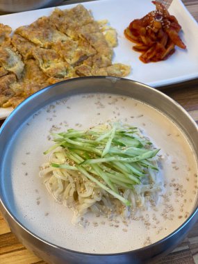 Kungguksu, taze sebzelerle kaplanmış ve yosunlarla süslenmiş lezzetli bir Kore soğuk şehriye çorbası. Yaz yemekleri için mükemmel, Kore konforlu yiyeceklerinin özünü yakalamak için..