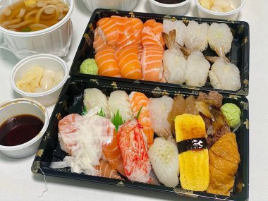 Çeşitli malzemeler ve canlı renklerle sanatsal olarak düzenlenmiş taze suşi çeşitleri. Bu geleneksel Japon yemeği bir deneyim için sirkeli pirinç, deniz ürünleri ve sebzeleri birleştirir..