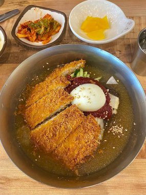 Soğuk naengmyeon erişteleri, dilimlenmiş sebze ve yumurtayla servis edilir. Çıtır çıtır altın donkatsu ile eşleştirilir. Bir öğünde ferahlatıcı ve lezzetli tatlar dengesi oluşturur.