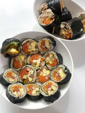 Taze sebzelerle, baharatlı pirinçlerle ve gevrek yosunlara sarılmış lezzetli proteinlerle dolu nefis kimbap dürümleri. Her ısırıkta lezzet ve dokuların mükemmel bir kombinasyonu.