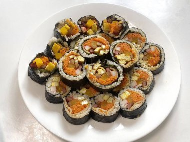 Taze sebzelerle, baharatlı pirinçlerle ve gevrek yosunlara sarılmış lezzetli proteinlerle dolu nefis kimbap dürümleri. Her ısırıkta lezzet ve dokuların mükemmel bir kombinasyonu.