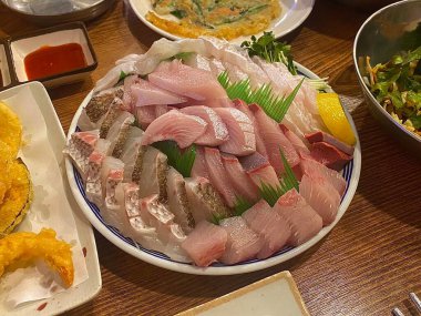 Taze ve narin sashimi dilimleri, canlı renkler ve mükemmel kesimlerle güzelce sunuluyor. Bu geleneksel Japon lezzeti kaliteli deniz ürünlerinin saf tatlarını vurgular..