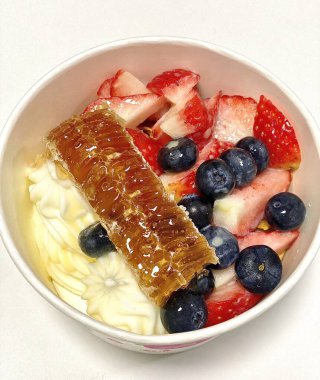 Doldurulmuş yoğurtlu tatlı bir fincanda servis ediliyor, pürüzsüz kremalı dokular, parlak yüzeyli, taze meyve parçaları ile kaplı, ferahlatıcı ve davetkar görünümünü detaylıca vurgulayan.