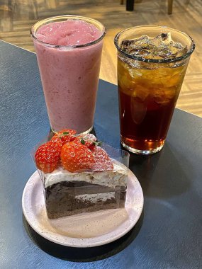 Hoş bir kafe ortamında sergilenen tatlı çeşitleri zarif tabaklar üzerinde pastalar, pastalar ve tatlı ikramlar, sıcak ve davetkar bir atmosfer yaratıyor..