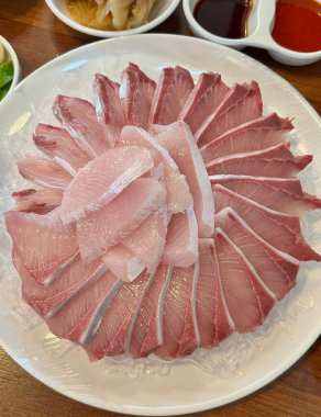 Taze ve narin sashimi dilimleri, canlı renkler ve mükemmel kesimlerle güzelce sunuluyor. Bu geleneksel Japon lezzeti kaliteli deniz ürünlerinin saf tatlarını vurgular..