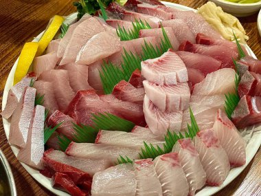 Taze ve narin sashimi dilimleri, canlı renkler ve mükemmel kesimlerle güzelce sunuluyor. Bu geleneksel Japon lezzeti kaliteli deniz ürünlerinin saf tatlarını vurgular..