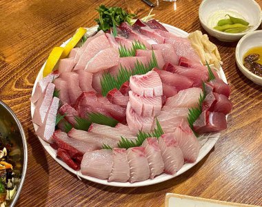 Taze ve narin sashimi dilimleri, canlı renkler ve mükemmel kesimlerle güzelce sunuluyor. Bu geleneksel Japon lezzeti kaliteli deniz ürünlerinin saf tatlarını vurgular..