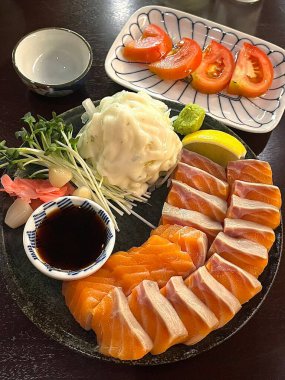 Taze ve narin sashimi dilimleri, canlı renkler ve mükemmel kesimlerle güzelce sunuluyor. Bu geleneksel Japon lezzeti kaliteli deniz ürünlerinin saf tatlarını vurgular..