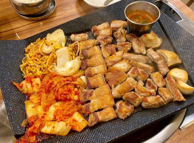 Izgara samgyeopsal, kalın domuz eti dilimleri çıtır çıtır ve taze et. Klasik bir Kore barbekü deneyimi için marul, sarımsak ve sosla servis ediliyor..