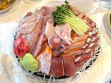 Taze ve narin sashimi dilimleri, canlı renkler ve mükemmel kesimlerle güzelce sunuluyor. Bu geleneksel Japon lezzeti kaliteli deniz ürünlerinin saf tatlarını vurgular..
