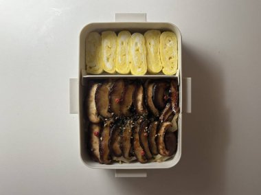 Bento or dosirak box filled with rice, assorted side dishes, vegetables, and protein like meat or fish, all neatly arranged to create a balanced, colorful, and visually appealing meal