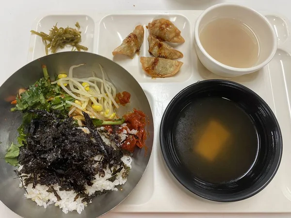 Bibimbap, çeşitli sebzeler, gochujang ve sıklıkla dilimlenmiş etin eşlik ettiği kızarmış yumurta ile süslenmiş canlı bir Kore pirinç yemeği. Karıştırıldığında, aromalı ve dengeli olur..