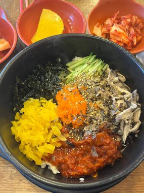 Bibimbap, çeşitli sebzeler, gochujang ve sıklıkla dilimlenmiş etin eşlik ettiği kızarmış yumurta ile süslenmiş canlı bir Kore pirinç yemeği. Karıştırıldığında, aromalı ve dengeli olur..