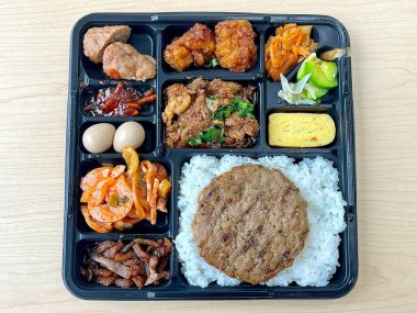 Bento or dosirak box filled with rice, assorted side dishes, vegetables, and protein like meat or fish, all neatly arranged to create a balanced, colorful, and visually appealing meal
