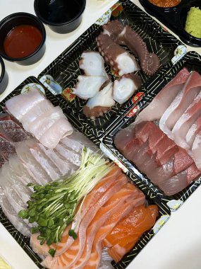 Taze ve narin sashimi dilimleri, canlı renkler ve mükemmel kesimlerle güzelce sunuluyor. Bu geleneksel Japon lezzeti kaliteli deniz ürünlerinin saf tatlarını vurgular..