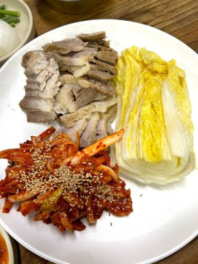 Yumuşak bir parça Bossam, Kore haşlanmış domuz göbeği, taze marul, sarımsak ve ssamjang ile servis edilir. Bu lezzetli ve lezzetli yemek geleneksel bir Kore yemeğini paketlemek ve paylaşmak için mükemmeldir..