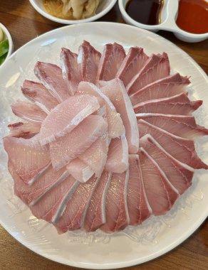 Taze ve narin sashimi dilimleri, canlı renkler ve mükemmel kesimlerle güzelce sunuluyor. Bu geleneksel Japon lezzeti kaliteli deniz ürünlerinin saf tatlarını vurgular..