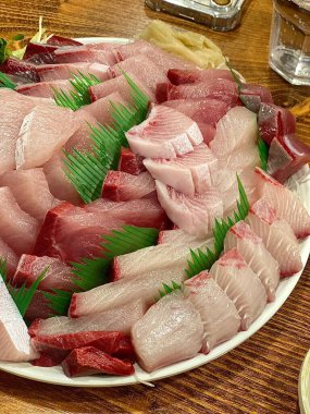 Taze ve narin sashimi dilimleri, canlı renkler ve mükemmel kesimlerle güzelce sunuluyor. Bu geleneksel Japon lezzeti kaliteli deniz ürünlerinin saf tatlarını vurgular..