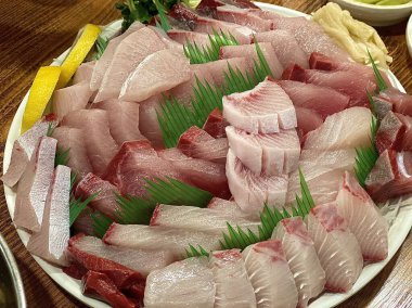 Taze ve narin sashimi dilimleri, canlı renkler ve mükemmel kesimlerle güzelce sunuluyor. Bu geleneksel Japon lezzeti kaliteli deniz ürünlerinin saf tatlarını vurgular..