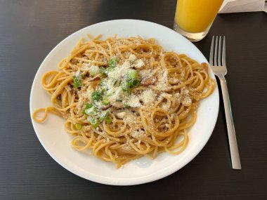 Bir tabak spagetti makarnası, mükemmel pişirilmiş ve üzerine bol marinara sosu ve taze otlar konmuş. Yemek fotoğrafçılığı ve menüler için ideal, İtalyan mutfağının kalbini lezzetli bir şekilde yakalamak..