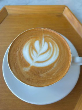 Çok güzel işlenmiş bir latte, kremalı köpüklü sanat eseri ve üstüne de espresso. Kahveyle ilgili projeler için mükemmel. Bu görüntü, klasik bir kafe deneyiminin sıcaklığını ve davetkar doğasını yansıtıyor..
