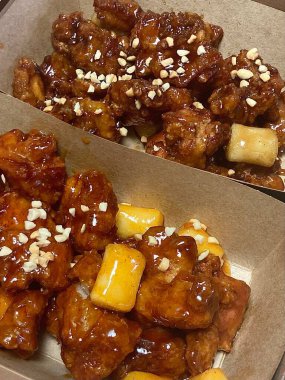 Kızarmış Kore tavuğu, tatlı ve baharatlı sosla mükemmel bir şekilde jölelenmiş. Yemek fotoğrafçılığı ve menüler için idealdir. Bu sevilen yemeğin dayanılmaz çıtırtısını ve lezzetini sergiler..