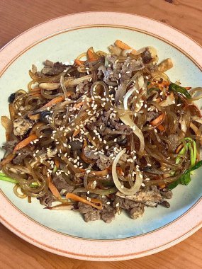 Canlı bir tabak japchae, kızarmış cam şehriye, renkli sebzeler, ve lezzetli soya sosuyla kaplanmış taze et. Klasik bir Kore favorisi.!