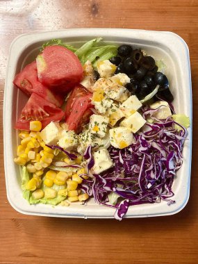 Taze salata taze yapraklı sebzeler, dilimlenmiş sebzeler ve rengarenk malzemelerin karışımı sağlıklı, canlı ve ferahlatıcı bir tat yaratmak için bir araya getirilmiş.