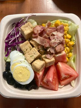 Taze salata taze yapraklı sebzeler, dilimlenmiş sebzeler ve rengarenk malzemelerin karışımı sağlıklı, canlı ve ferahlatıcı bir tat yaratmak için bir araya getirilmiş.